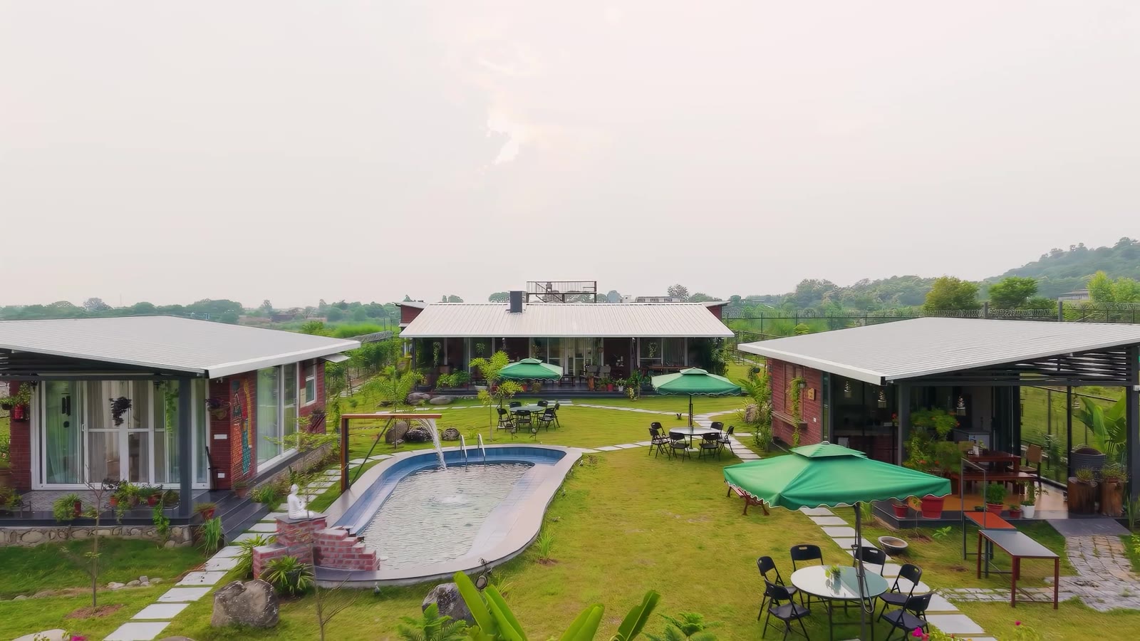 Sabr's cottages in a green landscape with pool and surrounding hills